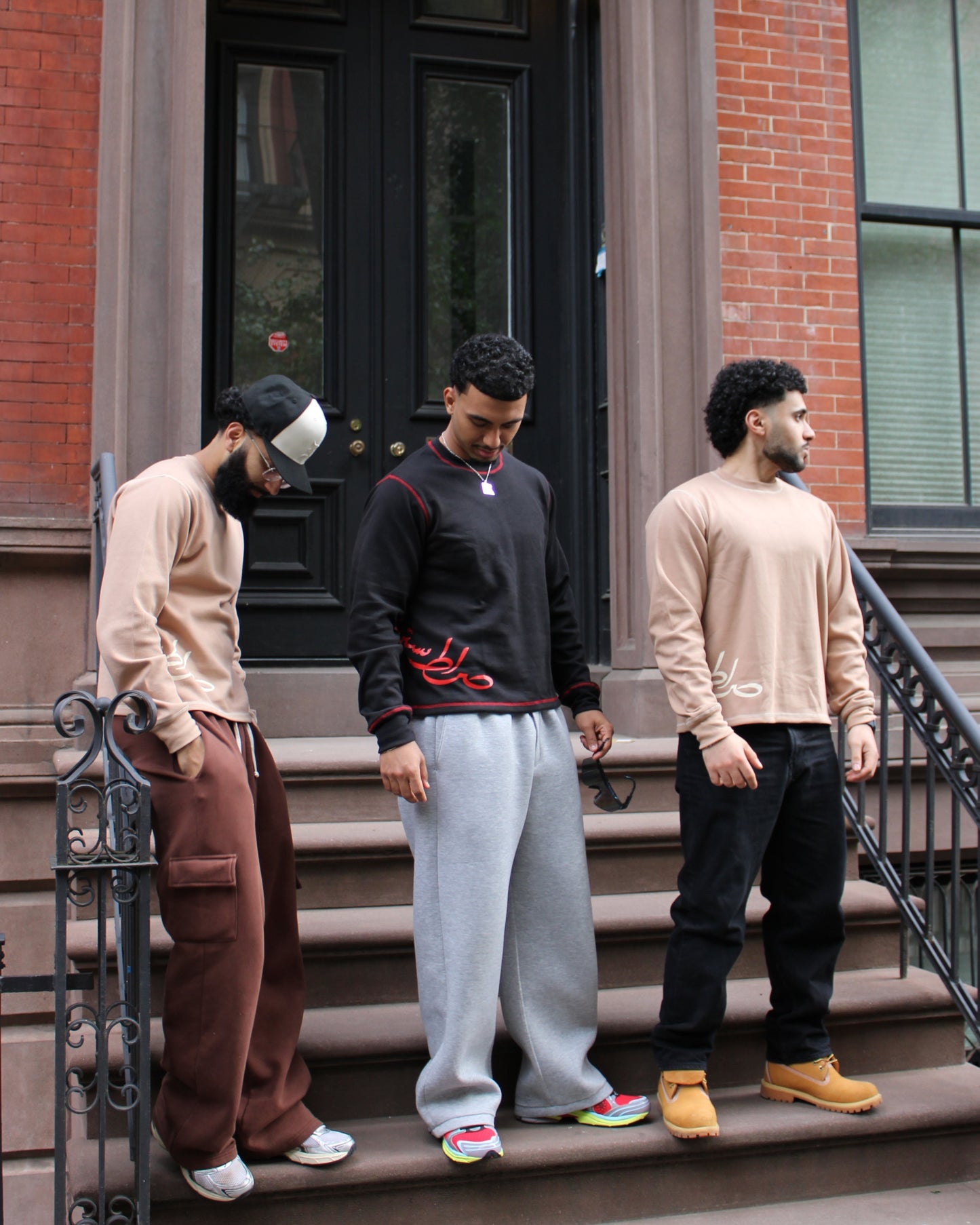 Three men standing on a set of stairs in front of a brick building.