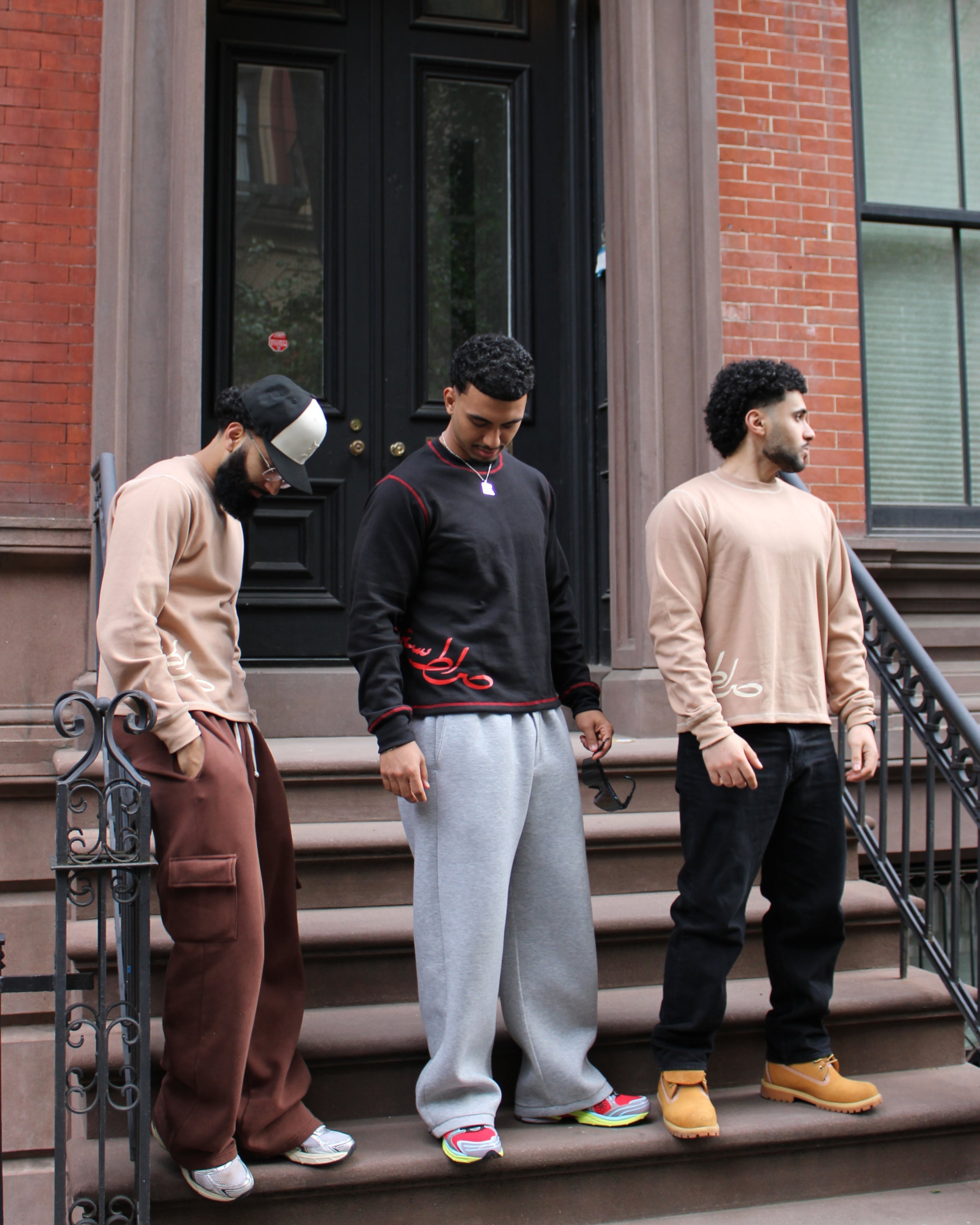Three men standing on a set of stairs in front of a brick building.